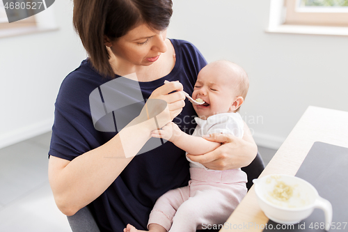 Image of middle-aged mother feeding baby daughter at home