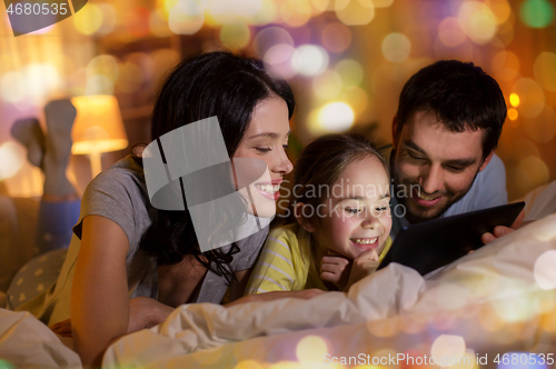 Image of family with tablet pc in bed at night at home