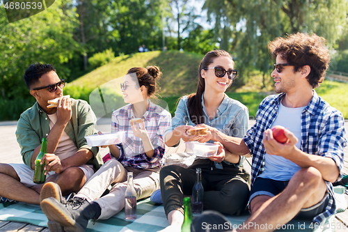 Image of happy friends having picnic at summer park