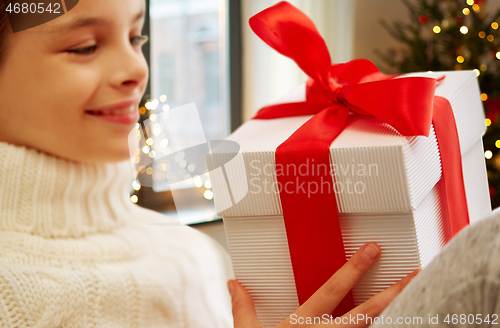 Image of happy beautiful girl with christmas gift at home