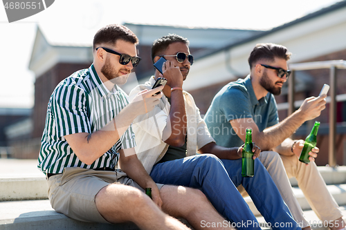 Image of men with smartphones drinking beer on street