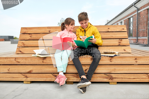 Image of school children with notebooks sitting on bench