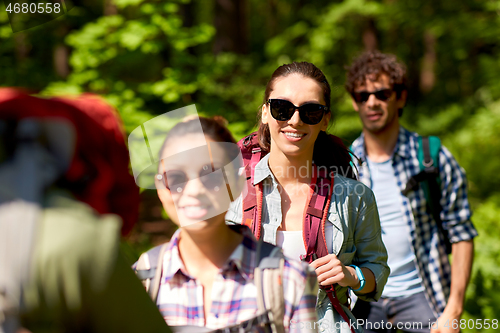 Image of group of friends with backpacks hiking in forest