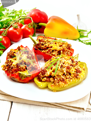 Image of Pepper stuffed with meat and couscous in white plate on wooden b