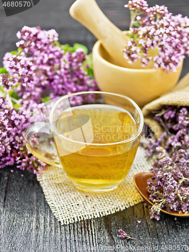 Image of Tea of oregano in cup with mortar on dark wooden board