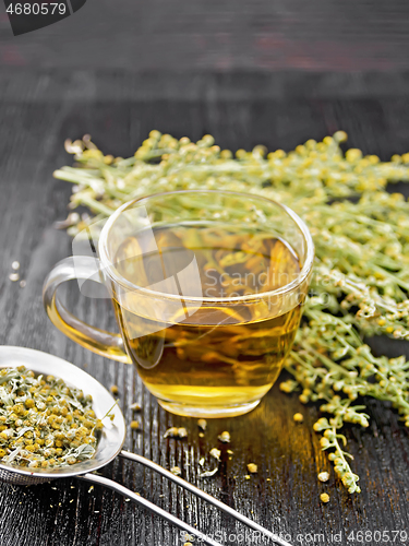 Image of Tea of gray wormwood in glass cup with strainer on black board