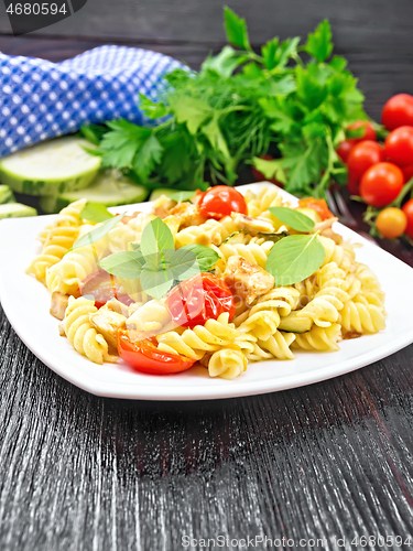 Image of Fusilli with chicken and tomatoes in plate on wooden board