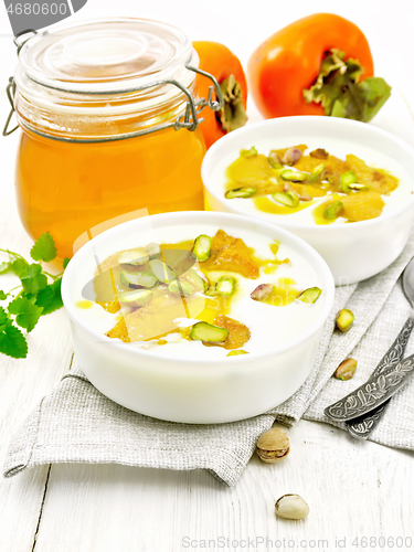 Image of Dessert of yogurt and persimmon two bowls on light wooden board