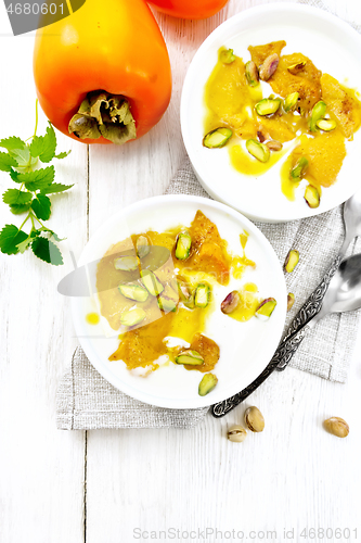 Image of Dessert of yogurt and persimmon two bowls on board top