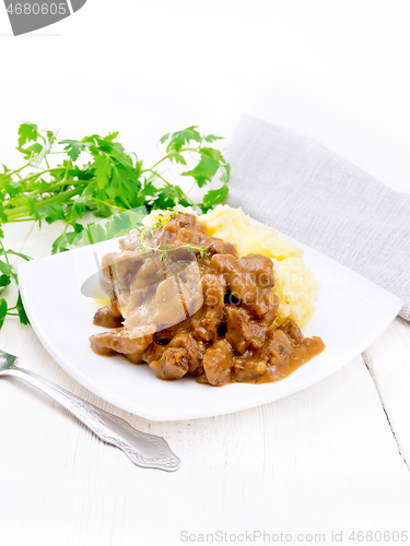 Image of Goulash of beef with mashed potatoes in plate on light wooden bo