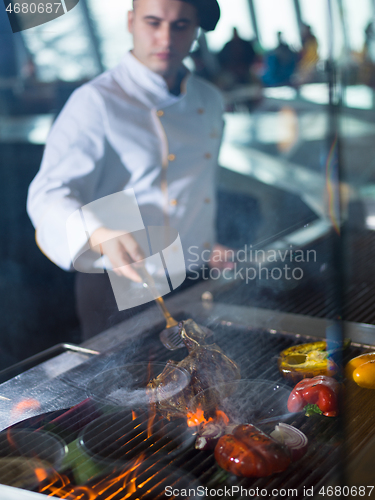 Image of chef cooking steak with vegetables on a barbecue