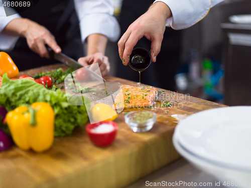 Image of Chef hands preparing marinated Salmon fish