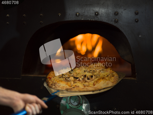 Image of chef removing hot pizza from stove