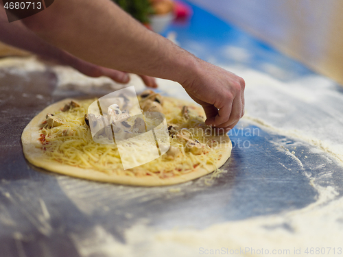 Image of chef putting fresh mushrooms on pizza dough