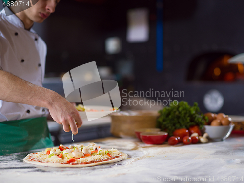 Image of chef putting fresh vegetables on pizza dough