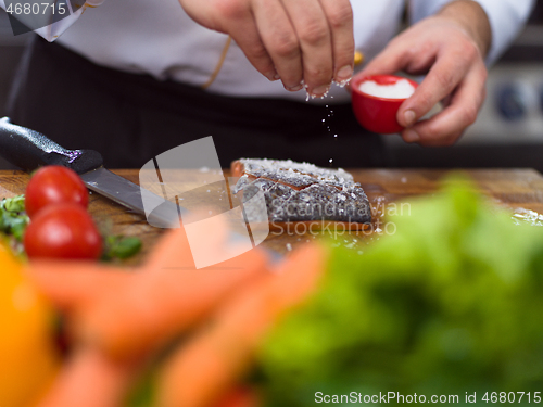 Image of Chef hands preparing marinated Salmon fish