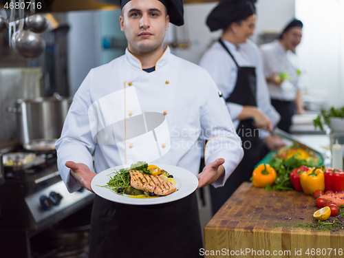 Image of Chef holding dish of fried Salmon fish fillet