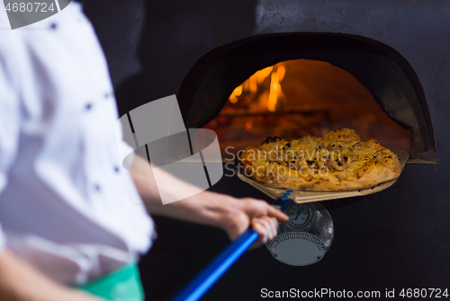 Image of chef removing hot pizza from stove