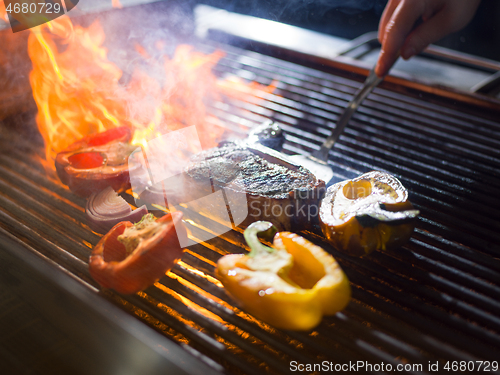 Image of chef cooking steak with vegetables on a barbecue