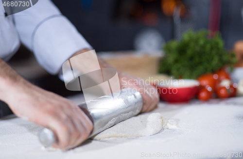 Image of chef preparing dough for pizza with rolling pin