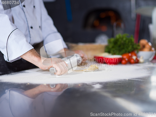 Image of chef preparing dough for pizza with rolling pin