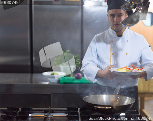 Image of chef preparing food, frying in wok pan