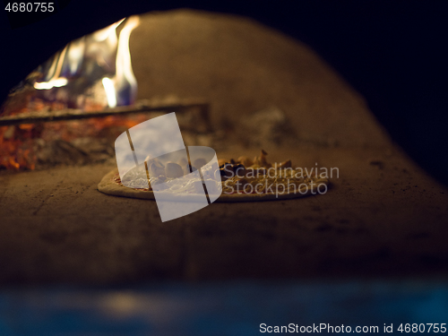 Image of chef putting delicious pizza to brick wood oven