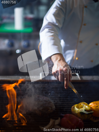 Image of chef cooking steak with vegetables on a barbecue