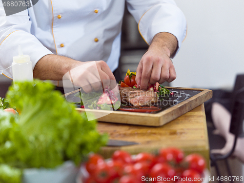 Image of closeup of Chef hands serving beef steak