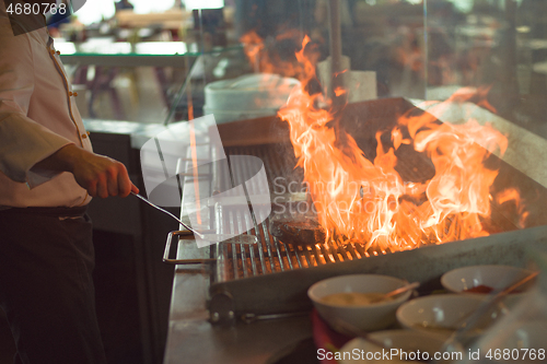 Image of chef cooking steak with vegetables on a barbecue