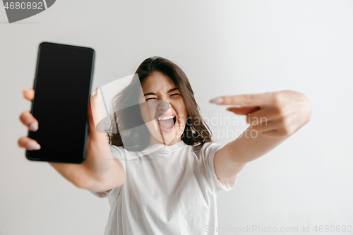 Image of Portrait of a confident casual asian girl showing blank screen of mobile phone