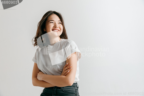 Image of Happy asian woman standing and smiling against gray background.