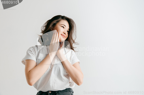 Image of Happy asian woman standing and smiling against gray background.