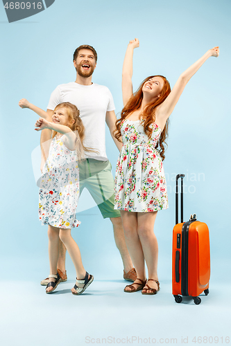 Image of Happy parent with daughter and suitcase at studio isolated on blue background