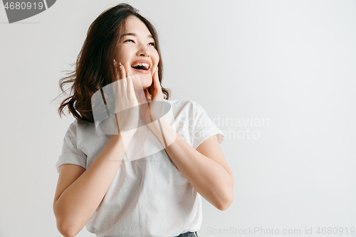 Image of Happy asian woman standing and smiling against gray background.