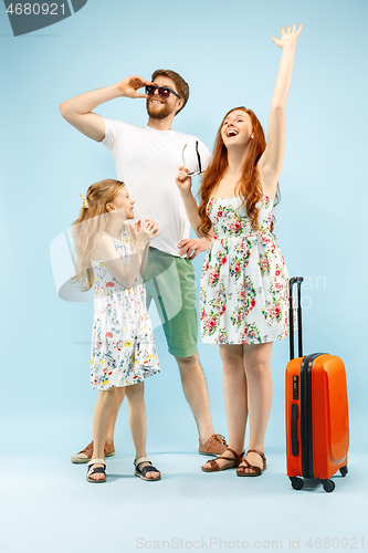 Image of Happy parent with daughter and suitcase at studio isolated on blue background