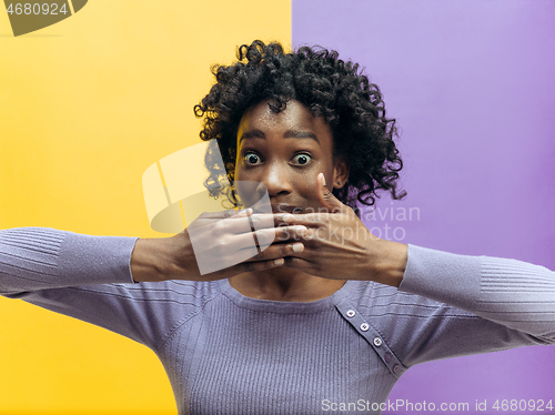 Image of The young woman whispering a secret behind her hand