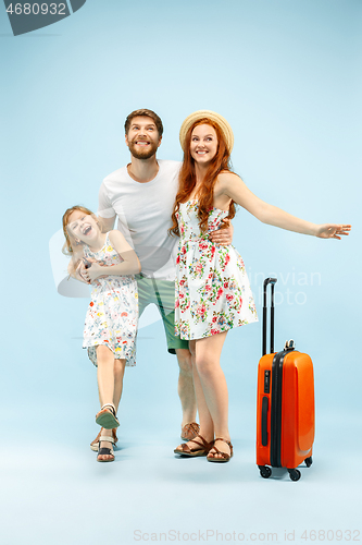 Image of Happy parent with daughter and suitcase at studio isolated on blue background