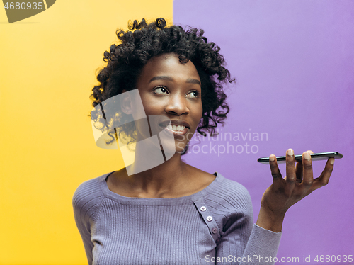 Image of Indoor portrait of attractive young black woman holding blank smartphone