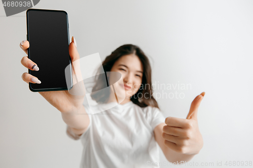 Image of Portrait of a confident casual asian girl showing blank screen of mobile phone