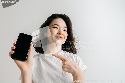 Image of Portrait of a confident casual asian girl showing blank screen of mobile phone