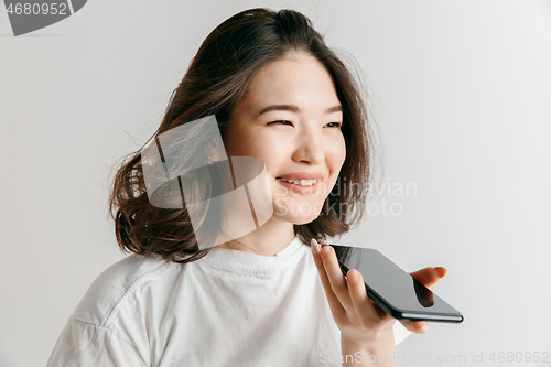 Image of Indoor portrait of attractive young asian woman holding blank smartphone