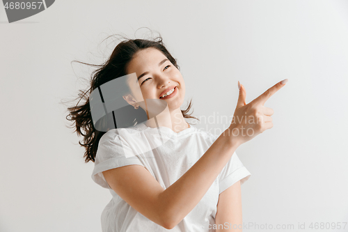 Image of The happy asian woman standing and smiling against gray background.