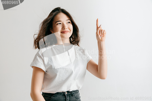 Image of The happy asian woman standing and smiling against gray background.