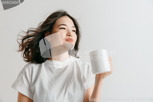 Image of Taking a coffee break. Handsome young man holding coffee cup while standing against gray background