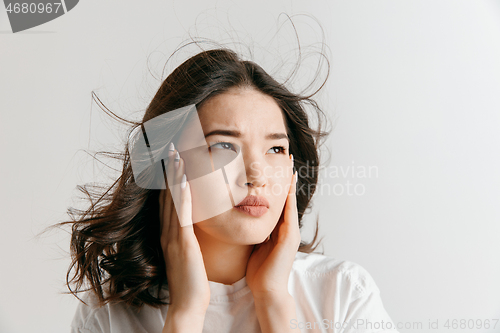 Image of Woman having headache. Isolated over gray background.