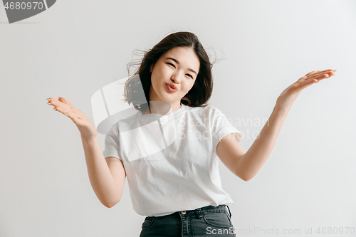 Image of The happy asian woman standing and smiling against gray background.