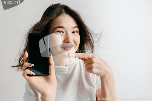 Image of Portrait of a confident casual asian girl showing blank screen of mobile phone