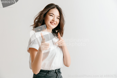 Image of The happy asian woman standing and smiling against gray background.