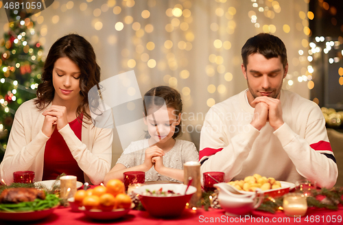 Image of family praying before meal at christmas dinner